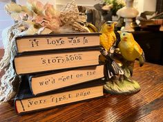 two yellow birds sitting on top of three books that are stacked on each other with the words if love was a storybook we'd get on the very first page