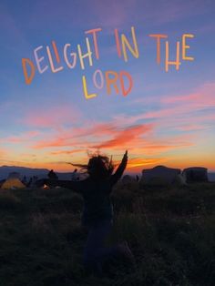 a woman sitting in the grass with her arms up and text that reads delight in the lord