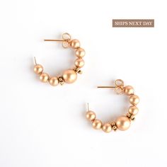 Our charming gold pearl hoop earrings are a chic and timeless accessory that will elevate any outfit. These earrings feature handmade gold filled hoops that are adorned with luminous gold crystal pearls, carefully selected for their quality and beauty. The small size of these earrings makes them perfect for everyday wear, while the classic design ensures that they will never go out of style. The pearls add a touch of sophistication and elegance to the hoops, creating a look that is both preppy a Gold Hoop Earrings With Round Beads, Gold 14k Gold-filled Hoop Earrings With Round Beads, Gold Hoop Pearl Earrings Minimalist Style, Gold Hoop Pearl Earrings In Minimalist Style, Gold Small Hoop Pearl Earrings For Everyday, Dainty Gold Hoop Earrings With Round Beads, Gold Hoop Earrings With Pearl Drop, Bryn Mawr, Christmas Gift For Mom