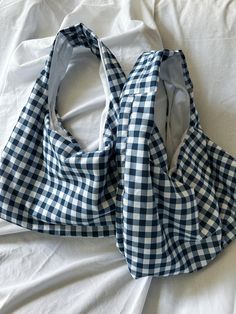 two blue and white bags sitting on top of a bed next to each other,