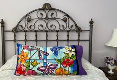 a bed with a metal headboard and colorful pillows on it's side table