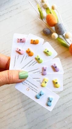 a person holding up four small animal erasers on top of a table next to some flowers