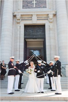 a bride and groom standing in front of a church with their wedding party holding flags