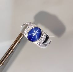 a diamond and lapel brooch sitting on top of a metal key with a blue stone in the middle