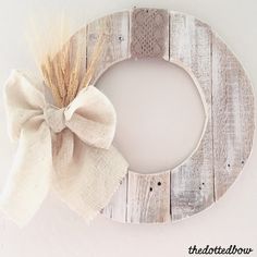 a wooden wreath with a bow hanging from it's side on a white wall