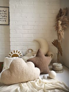 several pillows are arranged on a bed in front of a white brick wall and a plant