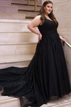 a woman in a long black dress standing on some steps with her hands on her hips