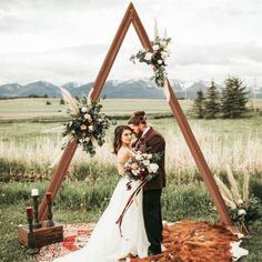 a bride and groom standing in front of a teepeet with flowers on it