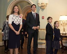 a group of people standing next to each other in front of a man wearing a suit and tie