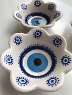 two blue and white bowls with an evil eye in the center on a counter top