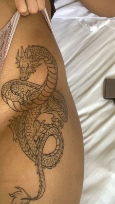 a woman laying in bed with a tattoo on her stomach and the side of her body