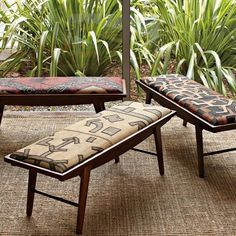 a bench and ottoman sitting on top of a rug in front of some plants,