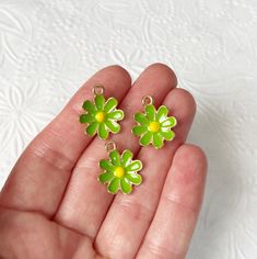 three small green flower charms sitting in someone's hand