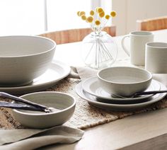 the table is set with dishes, cups and utensils