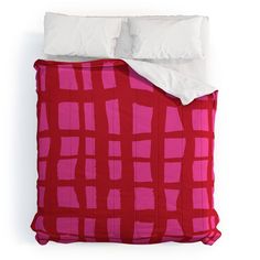 a red and white bed spread with two pillows on top of it, next to a pillow case