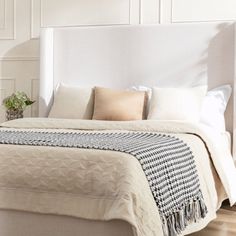 a white bed with pillows and blankets on it