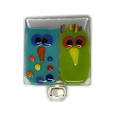 two green and blue glass magnets with faces on them, one is shaped like a bird