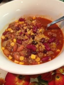 a white bowl filled with chili and corn on top of a flowery table cloth