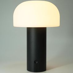 a black table lamp with a white light on the top and bottom part of it