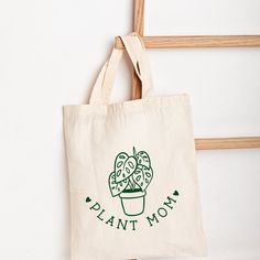 "Plant Mom Tote Bag, plant lover Christmas gift, Gardening Tote Bag, Crazy Plant Lady, Plant Mom, Plant mom gift, Gardener Gift, Trendy Get this beautiful Plant mom tote bag for the plant lover! Color:Naural Details: Length: 14 3/4\" Width: 15\" Handle Drop Length: 11 1/2\" Content: 100% Cotton Care: Hand Wash, Cold Water; Hang Dry Made with green Siser brand htv vinyl Shipping 1-2 days Check out my tote bags and digital downloads!" Green Canvas Bag With Eco-friendly Ink As Gift, Eco-friendly Green Bags For Gifts, Organic Tote Bag For Gifts, Eco-friendly Canvas Bag For Mother's Day, Eco-friendly Canvas Gift Bag, Plant Print Tote Bag For Gift, Plant Print Tote Bag As Gift, Eco-friendly Tote Canvas Bag For Mother's Day, Botanical Cotton Bags As Gift