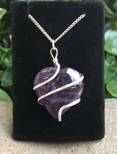 This listing is for an Amethyst Heart Wire Wrap Pendant with a silver plated chain. A few options are pictured to show the natural variation in the stone. Amethyst is a transparent to translucent stone that has a lavender to reddish violet hue. It is typically found with a clear to white translucent swirling pattern. It forms as crystals in geodes or in host stones. Amethyst translates from Greek to mean not intoxicated. Amethyst is a stone known to help prevent nightmares and alleviate headache Silver Amethyst Jewelry With Heart Charm, Heart Shaped Amethyst For Jewelry Making, Heart-shaped Amethyst For Jewelry Making, Sterling Silver Heart Necklace Wire Wrapped, Silver Wire Wrapped Necklace For Valentine's Day, Silver Wire Wrapped Jewelry For Valentine's Day, Valentine's Day Silver Wire Wrapped Necklaces, Valentine's Day Silver Wire Wrapped Jewelry, Heart Shaped Amethyst Jewelry For Wedding