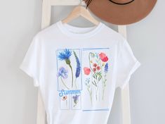 ✨Shop the latest deals, straight from small shops✨Unique Floral Tees - Wild Flower Shirt for Women - Florist Gift - Botanical Spring Flower Shirt - Blue Floral Graphic Tee - Best Friend Gift Embrace the beauty of nature with our stunning blue floral graphic tee! This unique shirt features a vibrant wildflower design, perfect for any flower lover or garden enthusiast. Made from soft, breathable fabric, this tee is ideal for spring and summer outings, adding a touch of botanical charm to your ward Blue Plant Print Summer Top, Blue Plant Print Top For Summer, Blue T-shirt For Spring, White Botanical Shirt For Summer, Botanical Style Shirt With Relaxed Fit For Summer, Botanical Style Relaxed Fit Shirt For Summer, White Botanical Style T-shirt For Summer, Spring Botanical Shirt With Relaxed Fit, Botanical Relaxed Fit Spring Shirt