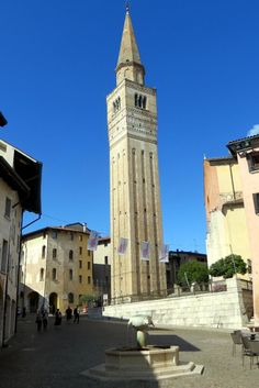 a tall tower with a clock on the top of it's side next to other buildings