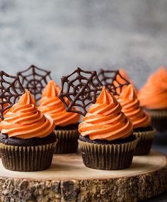 chocolate cupcakes with orange frosting and spider web decorations on the top one