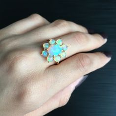 This gold ring features beautiful opals set in a prong setting in cluster. RING DETAILS: ✪Design: Gold cluster ring ✪Gemstone: Natural opal ✪Gemstone color: White ✪Gemstone shape: Oval, round ✪Gemstone size: 6mm*8mm, 4mm ✪Gemstone weight: 2.35 cts. ✪Setting type: Prong setting ✪Metal type: 14k solid gold ✪Gold weight: 2.91 gm ✪Metal finish: Smooth shiny ✪Total ring weight: 3.38 gm Choose your ring size from drop down menu and if you need any other preferred ring size please contact us. QUALITY O Cluster Multi-stone Opal Ring For Anniversary, Elegant Multi-stone Cluster Opal Ring, Elegant Cluster Opal Ring, October Birthstone Ring, October Birthstone Rings, Ring Cluster, Engagement Ring For Women, Cluster Engagement Ring, Cabochon Ring