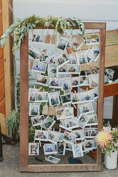 a wooden frame with photos attached to it and flowers on the table next to it