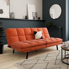 an orange couch sitting in a living room on top of a hard wood floor next to a table