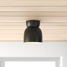 a black light hanging from the ceiling in a room with white walls and wooden slats