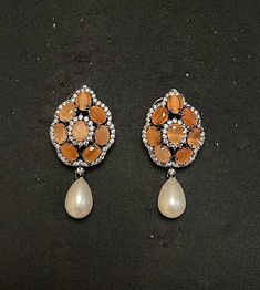 PUNJABI BRIDAL JEWELRY - WOMEN'S TRADITIONAL ORANGE ONYX & PEARL DROP EARRING Elegant set of earrings with beautiful orange onyx & CZ mini crystal. A versatile pair of earrings with orange onyx & Pearl drop. The engraved silver plated earring of traditional design adds an artisanal touch to the earrings. Details: Handcrafted Jewelry Metal: Metal Alloy, Silver Plated Stone:  Orange Onyx, CZ Crystal & Pearl Drop Style: Contemporary yet Traditional Closure:  Push back clasp B Anu Designs jewelry pi Elegant Orange Flower Earrings For Gift, Elegant Orange Earrings For Formal Occasions, Elegant Pear-shaped Orange Jewelry, Elegant Orange Pear-shaped Jewelry, Orange Pear-shaped Jewelry, Festive Teardrop Pearl Drop Earrings, Orange Teardrop Jewelry For Wedding, Orange Dangle Earrings For Formal Occasions, Orange Drop Earrings For Formal Occasions