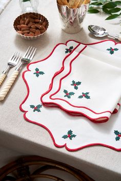 a white table topped with two place mats and silverware next to a bowl of nuts