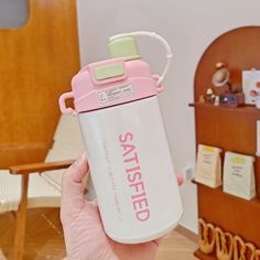 a person holding a pink and white water bottle with the word satisfied on it's side