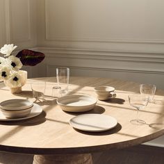 the table is set with white dishes and place settings for four people to enjoy their meal