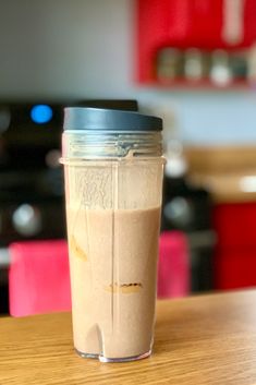 a smoothie in a cup sitting on top of a wooden table