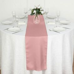 the table is set with white plates and pink napkins