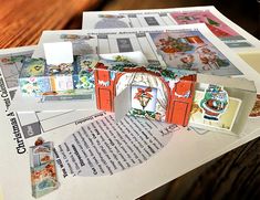 an open book on top of a pile of papers with pictures and letters cut out