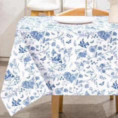 a blue and white floral tablecloth on a dining room table with two chairs in the background