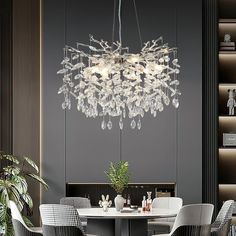 a chandelier hanging over a table in a room with chairs and a potted plant