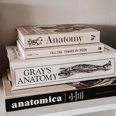 three books stacked on top of each other in front of a white wall with the title gray's anatomy