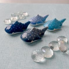 five glass whale figurines sitting on top of a blue cloth covered tablecloth