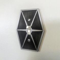 a black and silver wall light with two lights on it's sides, in the shape of a pentagon