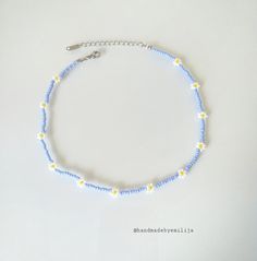 a blue and yellow beaded necklace on a white surface