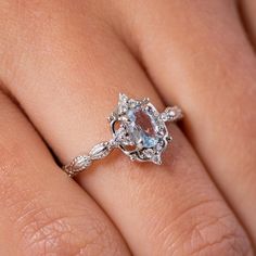 a woman's hand with a ring on it and an oval blue stone in the middle