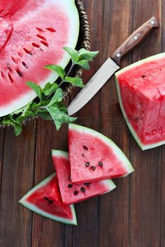 slices of watermelon on a wooden table with a knife