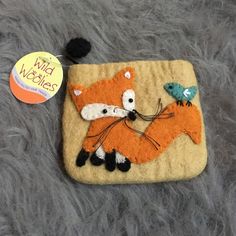 an orange and black felt bag with a fox and bird applique on it