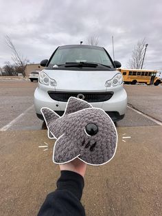 a person holding up a sticker with a cat on it's face in front of a car