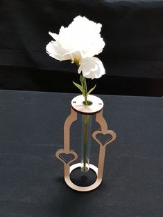 a white flower sitting in a vase on top of a black table with hearts cut out of it